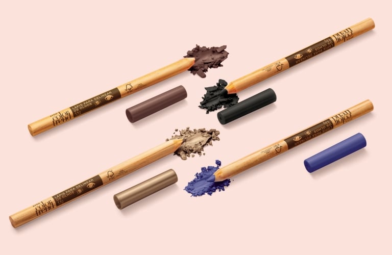 Quatro delineadores coloridos da Color Trend Avon nas cores azul, bege, preto e marrom estão deitados na horizontal e em fundo bege neutro.